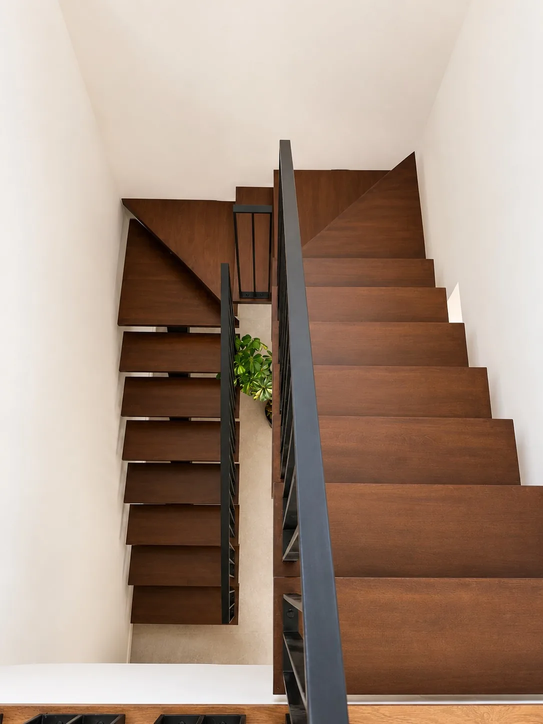 Escalera volada de madera de nogal con barandilla de lamas negras